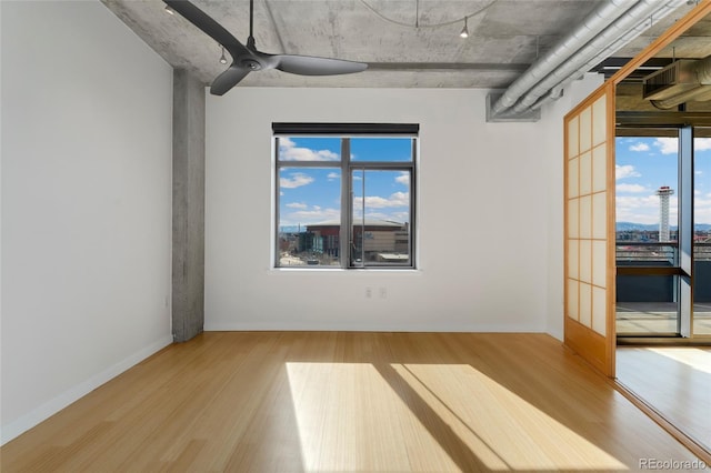 unfurnished room with ceiling fan, wood finished floors, and baseboards