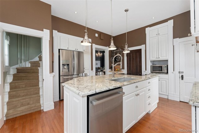 1154 N Clarkson St, Denver, CO 80218 - kitchen with stainless steel appliances, white cabinets, a kitchen island with sink, and light wood-type flooring