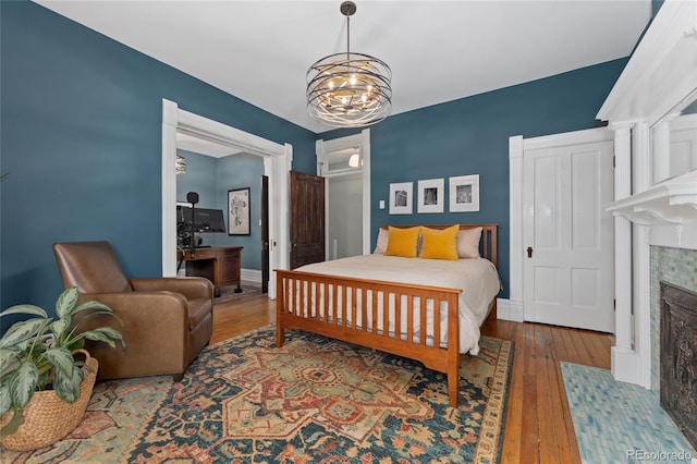 1154 N Clarkson St, Denver, CO 80218 - bedroom featuring a tiled fireplace, hardwood / wood-style floors, and a chandelier