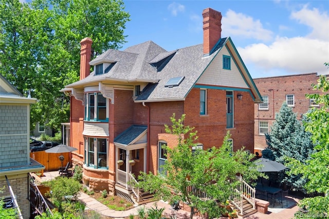 1154 N Clarkson St, Denver, CO 80218 - rear view of house featuring a patio area, a chimney, brick siding, and roof with shingles