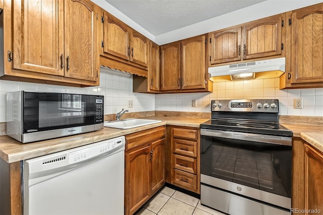 675 Straight Creek Dr Unit 301, Dillon, CO 80435 - kitchen featuring stainless steel appliances, under cabinet range hood, light countertops, brown cabinets, and a textured ceiling