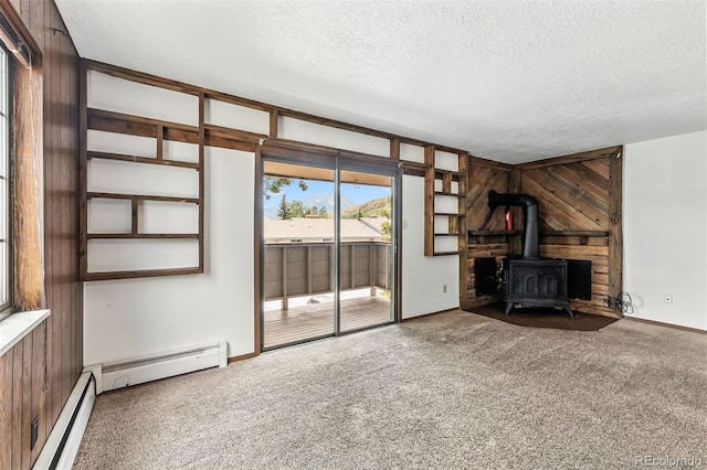 675 Straight Creek Dr Unit 301, Dillon, CO 80435 - unfurnished living room featuring a textured ceiling, carpet flooring, a wood stove, wooden walls, and a baseboard heating unit