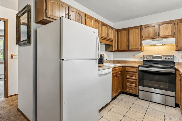675 Straight Creek Dr Unit 301, Dillon, CO 80435 - kitchen with appliances with stainless steel finishes, light countertops, under cabinet range hood, decorative backsplash, and brown cabinetry