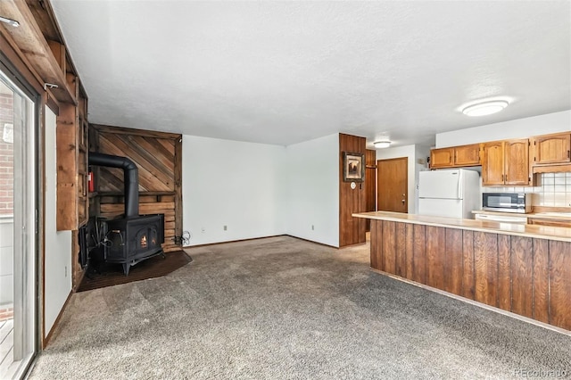 675 Straight Creek Dr Unit 301, Dillon, CO 80435 - kitchen with light countertops, light colored carpet, freestanding refrigerator, a wood stove, and stainless steel microwave