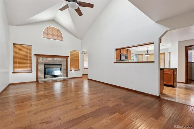 13457 Glen Cir, Broomfield, CO 80020 - unfurnished living room featuring ceiling fan, light wood finished floors, high vaulted ceiling, and a fireplace