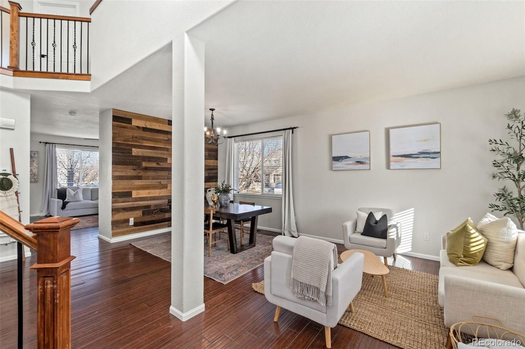 living room featuring plenty of natural light, dark hardwood / wood-style flooring, wood walls, and a chandelier