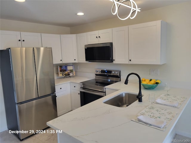 kitchen with kitchen peninsula, white cabinetry, sink, and appliances with stainless steel finishes