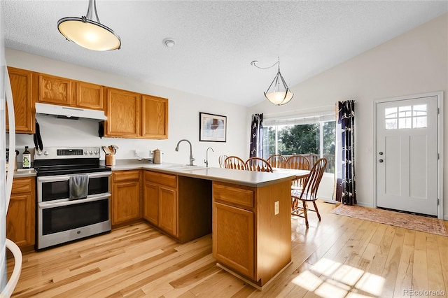 2659 S Halifax St, Aurora, CO 80013 - kitchen with double oven range, under cabinet range hood, a peninsula, vaulted ceiling, and brown cabinetry
