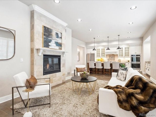 living room featuring hardwood / wood-style floors, sink, and a tile fireplace