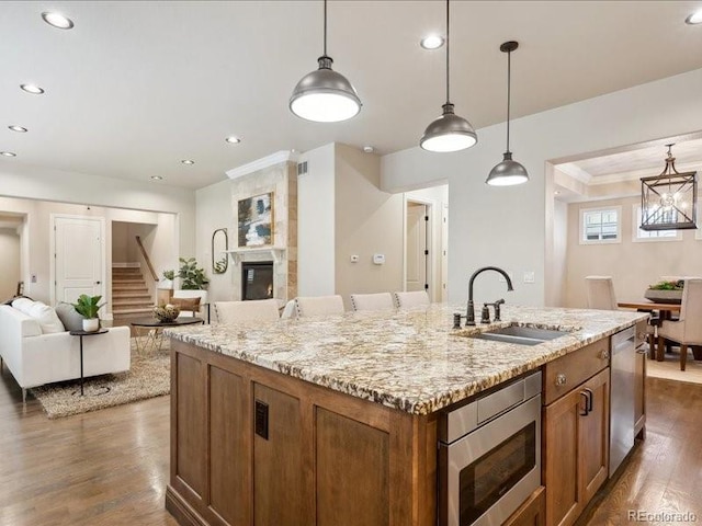 kitchen featuring stainless steel appliances, sink, a center island with sink, dark hardwood / wood-style floors, and hanging light fixtures