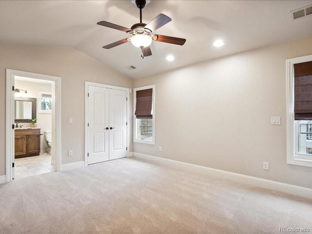 unfurnished bedroom with connected bathroom, ceiling fan, light colored carpet, and lofted ceiling