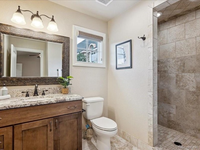 bathroom with tiled shower, vanity, toilet, and tile patterned flooring