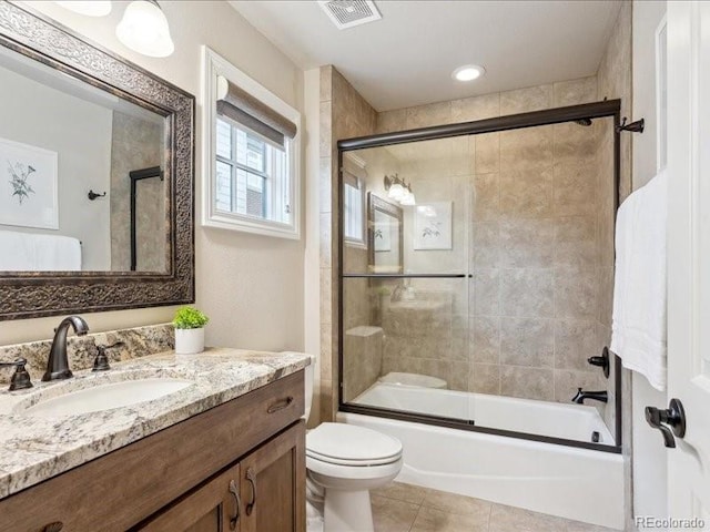 full bathroom featuring shower / bath combination with glass door, vanity, toilet, and tile patterned flooring