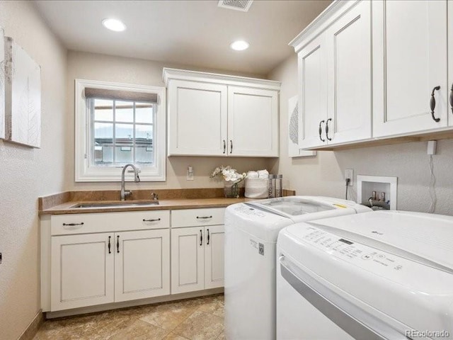 laundry area featuring washing machine and dryer, sink, and cabinets