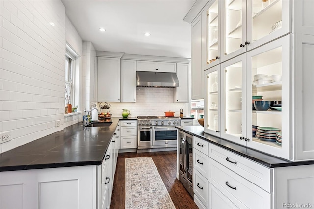 kitchen with double oven range, backsplash, wine cooler, white cabinets, and sink