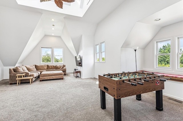 recreation room with ceiling fan, lofted ceiling, light carpet, and a healthy amount of sunlight