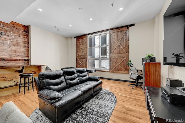 living room featuring a barn door, wooden walls, and hardwood / wood-style flooring