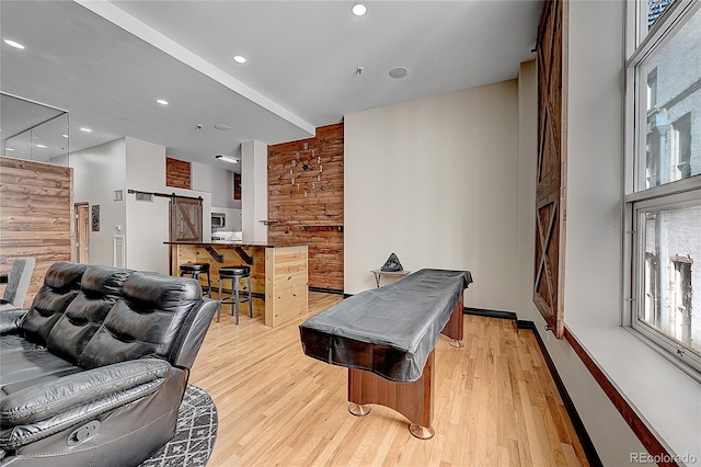 playroom featuring a barn door, pool table, and light hardwood / wood-style flooring