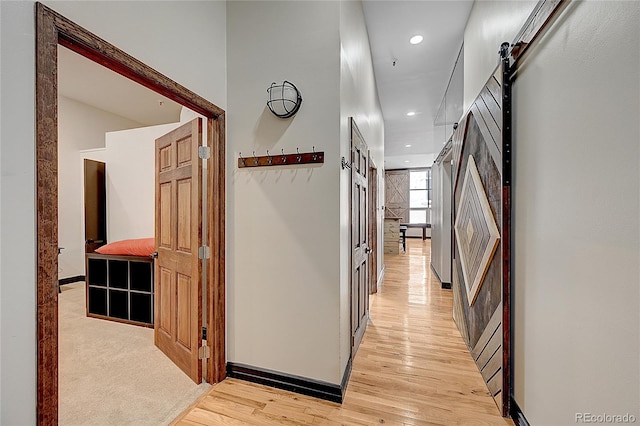 corridor with light hardwood / wood-style floors and a barn door