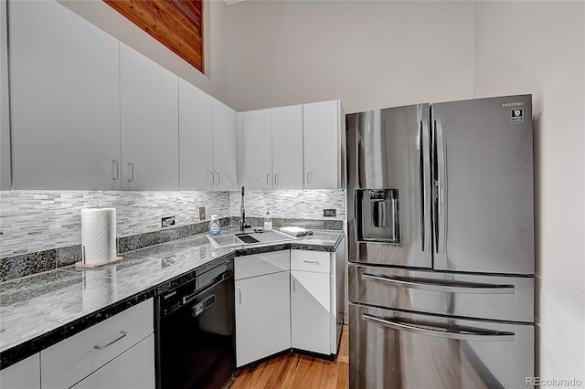 kitchen with light wood-type flooring, dishwasher, stainless steel fridge with ice dispenser, sink, and white cabinetry