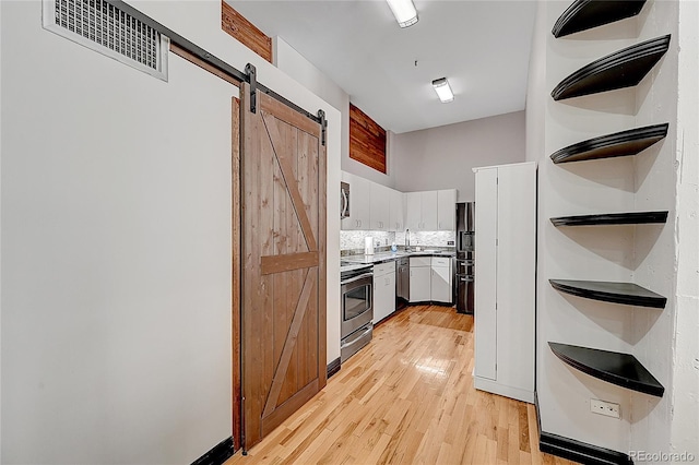 kitchen featuring sink, white cabinets, a barn door, light hardwood / wood-style flooring, and stainless steel appliances