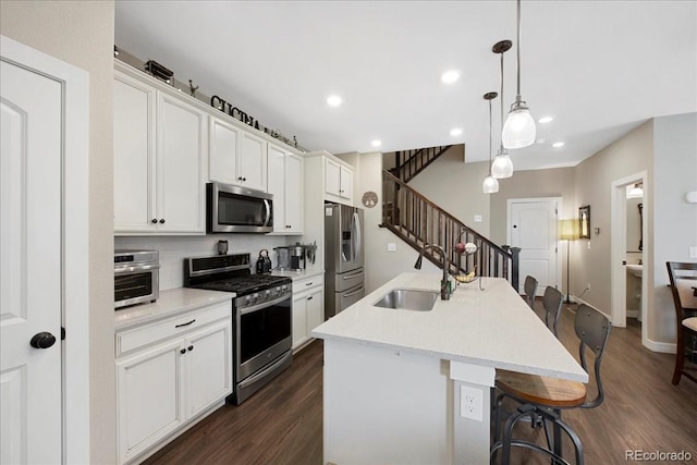 kitchen featuring appliances with stainless steel finishes, sink, a breakfast bar area, white cabinets, and a center island with sink