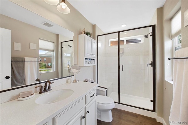 bathroom with wood-type flooring, toilet, an enclosed shower, and vanity