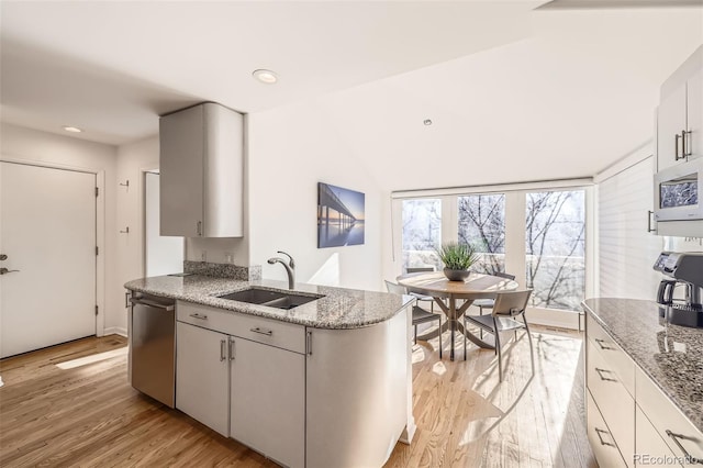 kitchen featuring sink, stainless steel dishwasher, light wood-type flooring, light stone counters, and white cabinetry