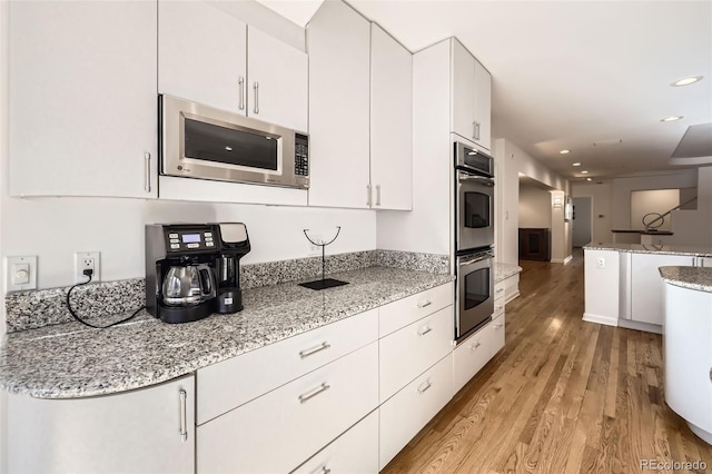 kitchen with white cabinets, light stone countertops, and appliances with stainless steel finishes