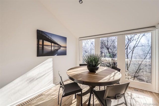 dining room featuring light wood-type flooring and high vaulted ceiling