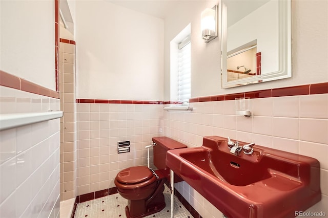 bathroom featuring tile patterned floors, toilet, and tile walls