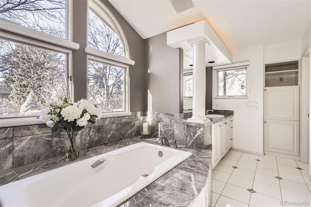 bathroom featuring vanity, plenty of natural light, ornate columns, and tiled bath