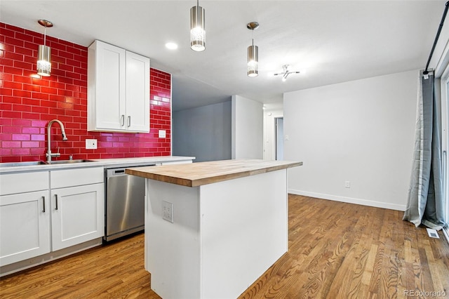 6948 W 70th Ave, Arvada, CO 80003 - kitchen featuring a sink, wood counters, white cabinetry, stainless steel dishwasher, and a kitchen island