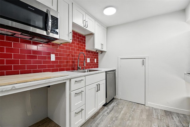 6948 W 70th Ave, Arvada, CO 80003 - kitchen with light countertops, white cabinetry, a sink, appliances with stainless steel finishes, and backsplash