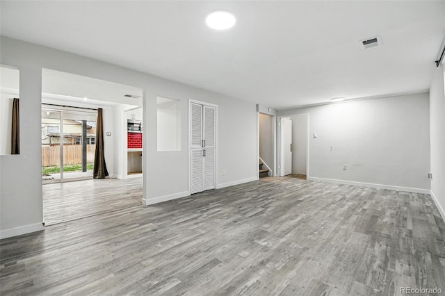 6948 W 70th Ave, Arvada, CO 80003 - unfurnished living room with stairs, baseboards, visible vents, and wood finished floors