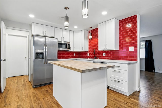 6948 W 70th Ave, Arvada, CO 80003 - kitchen featuring appliances with stainless steel finishes, wooden counters, a sink, white cabinets, and decorative light fixtures
