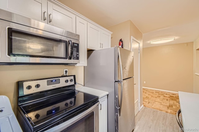 kitchen with stainless steel appliances, white cabinetry, washer and dryer, and light hardwood / wood-style flooring