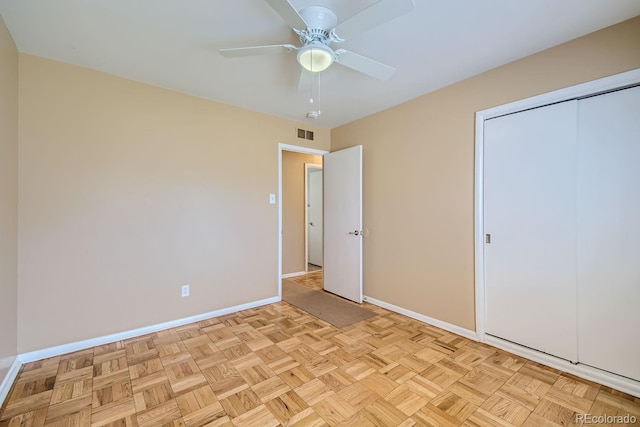 unfurnished bedroom with light parquet flooring, ceiling fan, and a closet