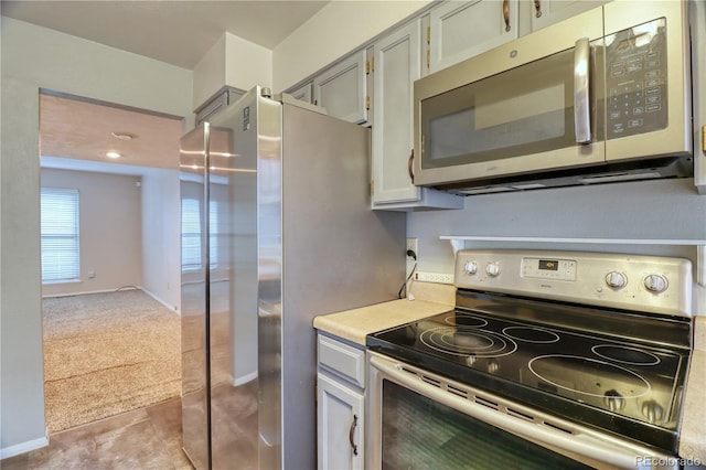 10320 E Jewell Ave Unit 63, Aurora, CO 80247 - kitchen with appliances with stainless steel finishes, light colored carpet, light countertops, baseboards, and light tile patterned flooring