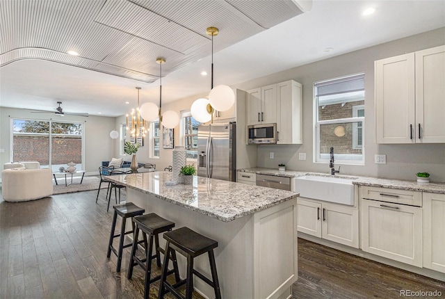 kitchen featuring sink, hanging light fixtures, appliances with stainless steel finishes, a kitchen island, and white cabinets