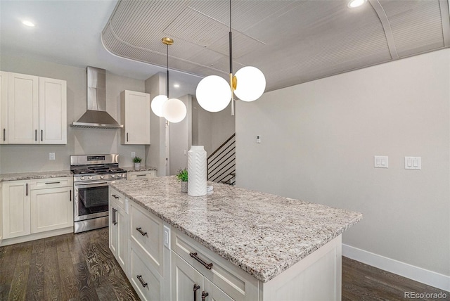 kitchen with gas range, decorative light fixtures, a center island, wall chimney range hood, and white cabinets