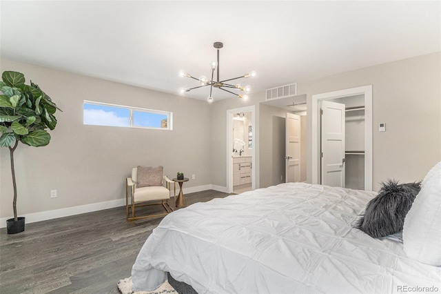 bedroom with ensuite bathroom, a spacious closet, a chandelier, a closet, and hardwood / wood-style flooring