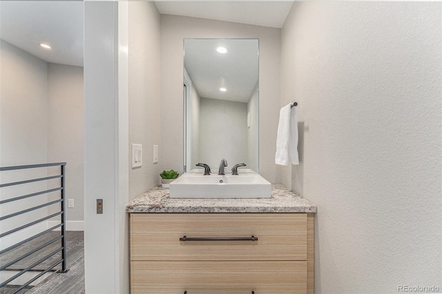 bathroom with hardwood / wood-style flooring, vanity, and vaulted ceiling