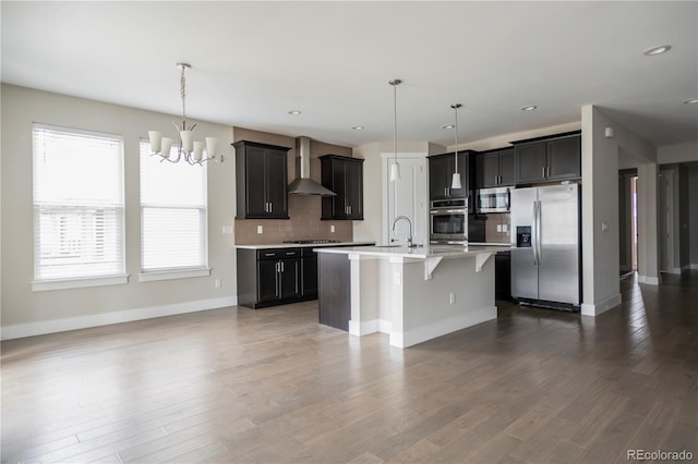 kitchen with stainless steel appliances, a kitchen breakfast bar, light countertops, wall chimney exhaust hood, and tasteful backsplash