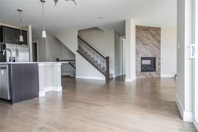 kitchen with stainless steel appliances, open floor plan, a fireplace, and light wood-style floors