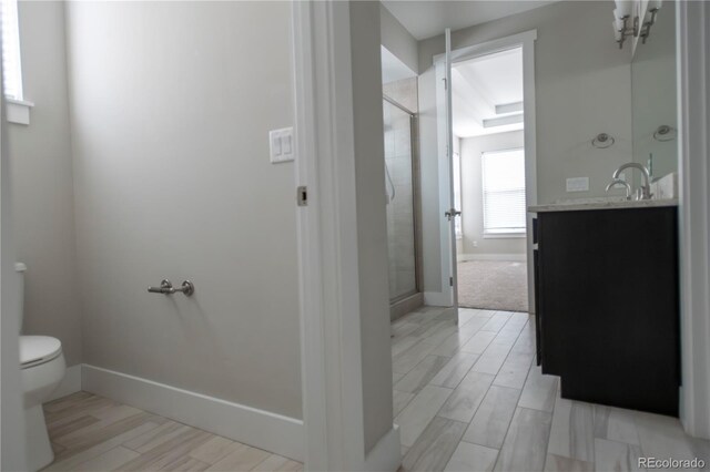 bathroom with vanity, a shower stall, toilet, and baseboards