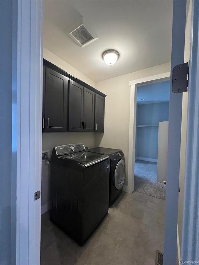 clothes washing area featuring visible vents, baseboards, cabinet space, and washer and dryer