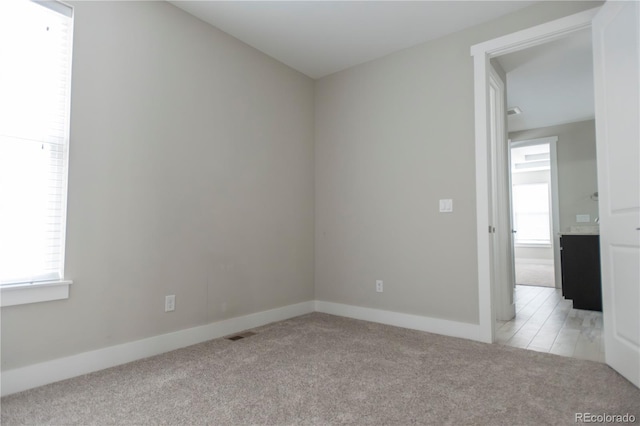 unfurnished room with light carpet, visible vents, and baseboards