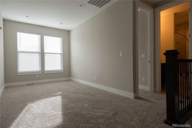 empty room with carpet, visible vents, and baseboards