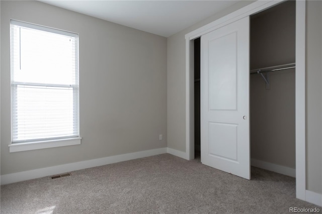 unfurnished bedroom with carpet, a closet, visible vents, and baseboards